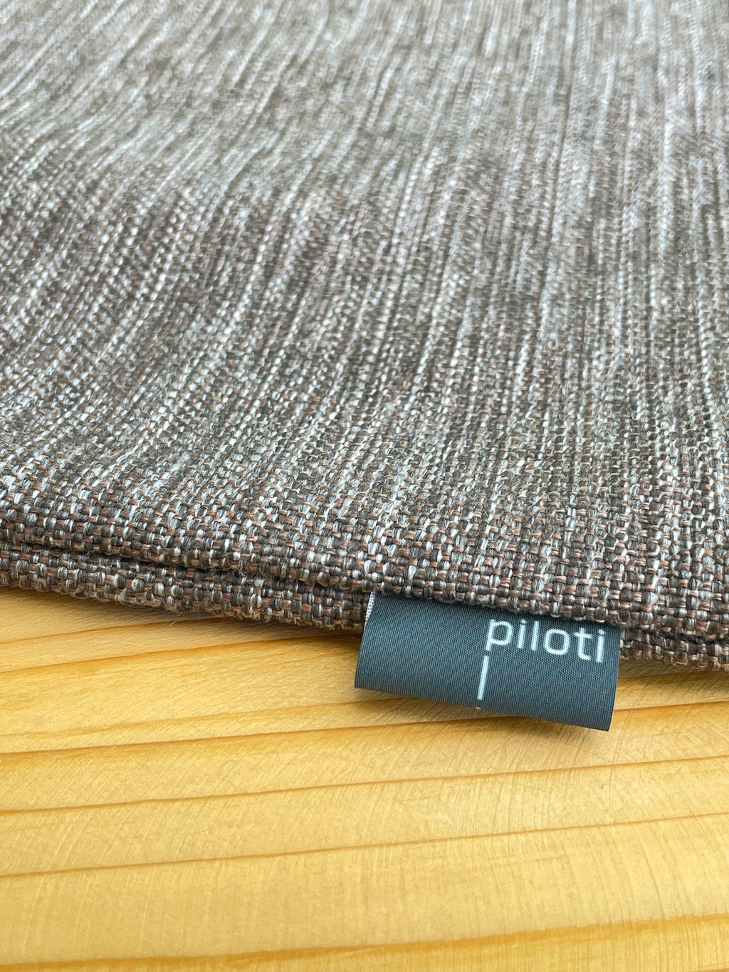 Textured fabric with a 'piloti' label on a wooden surface